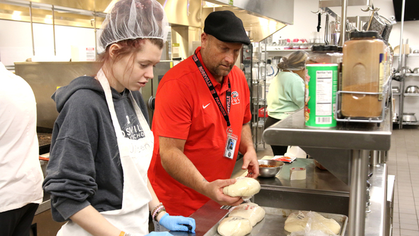 Hospitality Management Teacher Shawn Thompson works with RHS senior Lilli DeBusschere.